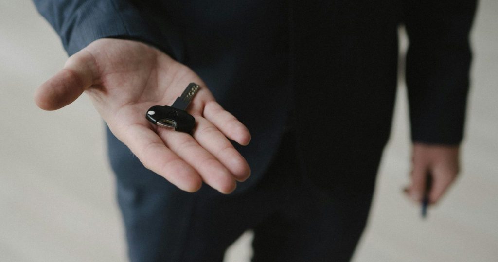 Close-up of a businessman in a suit holding car keys, inviting gesture.