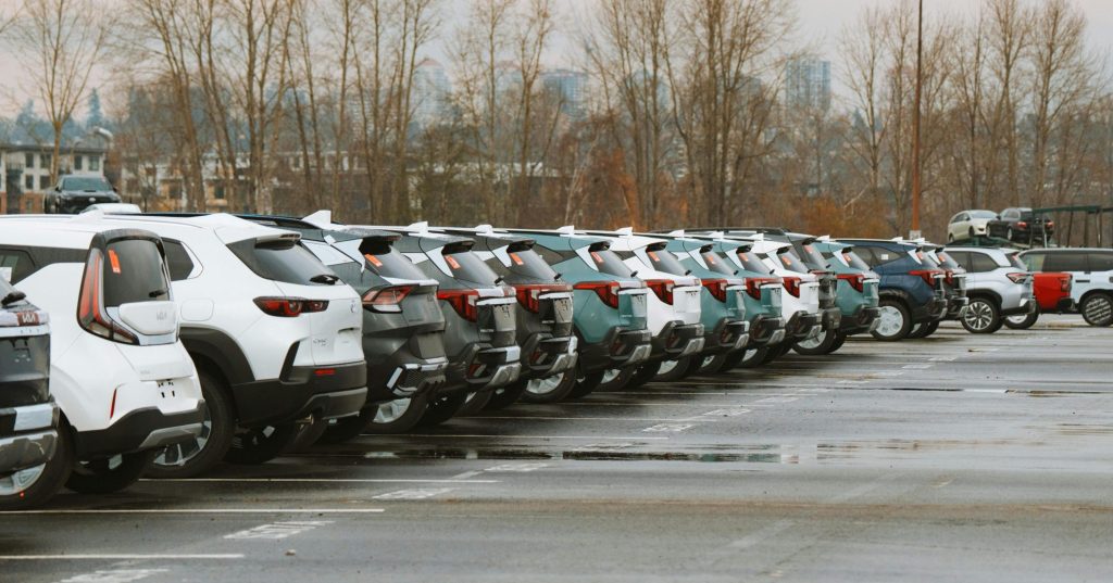 A line of parked cars in an outdoor urban parking lot on a cloudy day.