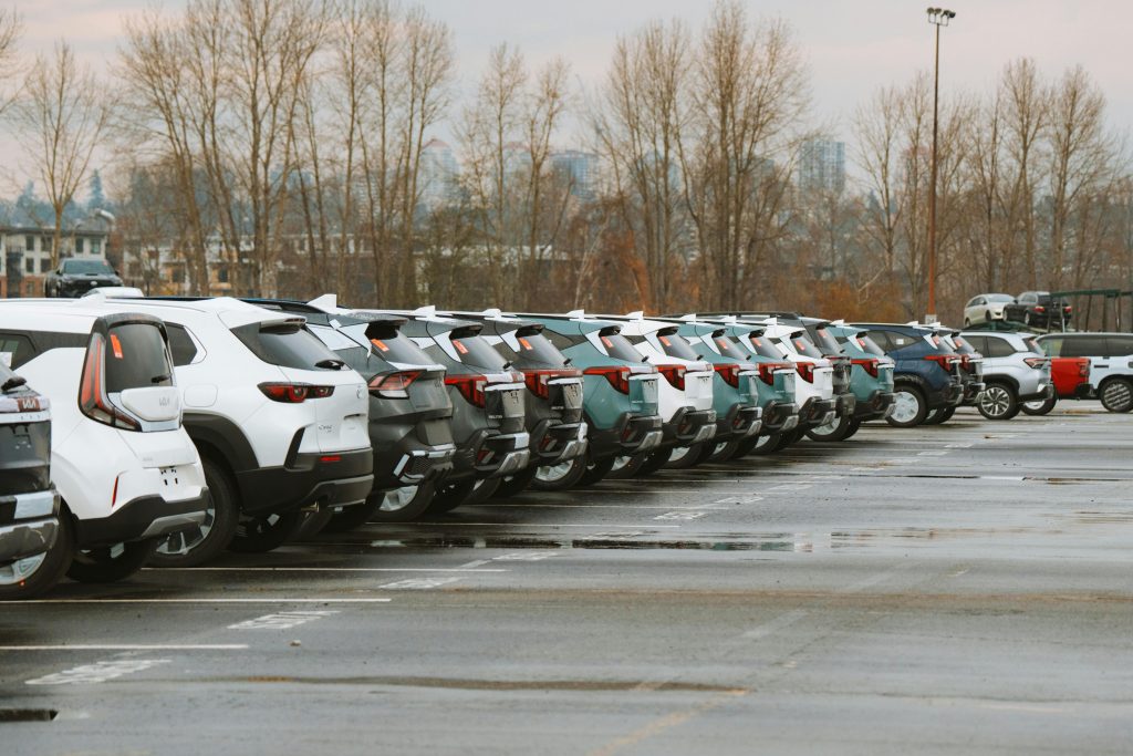 A line of parked cars in an outdoor urban parking lot on a cloudy day.
